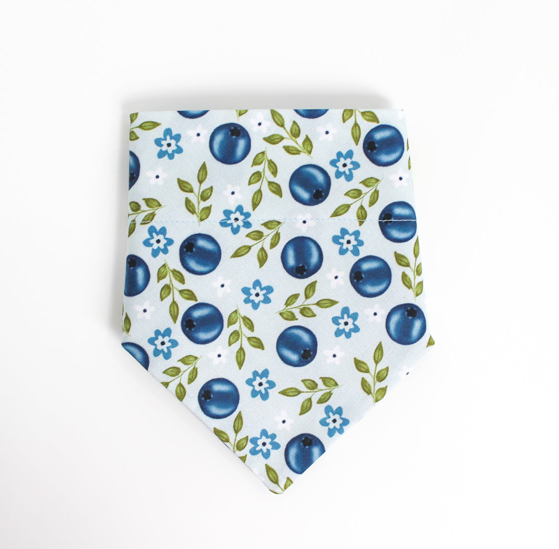 A light blue pet bandana featuring a repeating pattern of blue blueberries, green leaves, and small blue flowers, displayed flat against a clean white background.