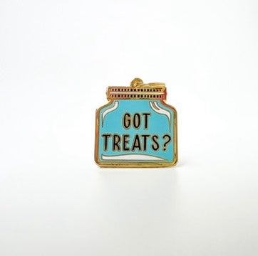 A small enamel pin shaped like a medicine bottle with the words 'GOT TREATS?' in gold lettering on a light blue background, outlined in gold, photographed on a plain white background.