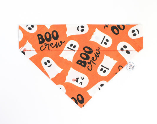 An orange pet bandana featuring a white and black 'BOO crew' ghost pattern, laid flat on a white background.