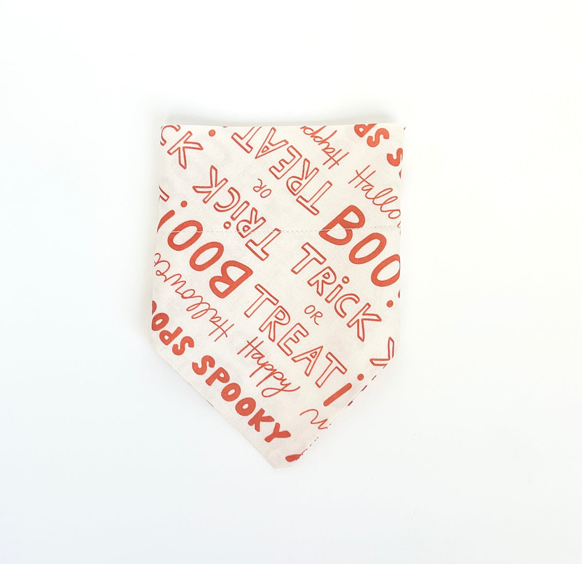 A triangular bandana-style pet collar or scarf in off-white fabric with a orange Halloween-themed print featuring words like 'BOO', 'TREAT or 'TRICK', and 'SPOOKY', shown on a plain white background.