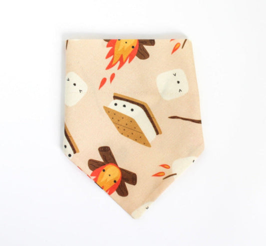 A light peach over the collar bandana-style pet collar featuring a cute cartoon s'mores print with marshmallows, campfires, and a s'mores sandwich, shown on a plain white background.